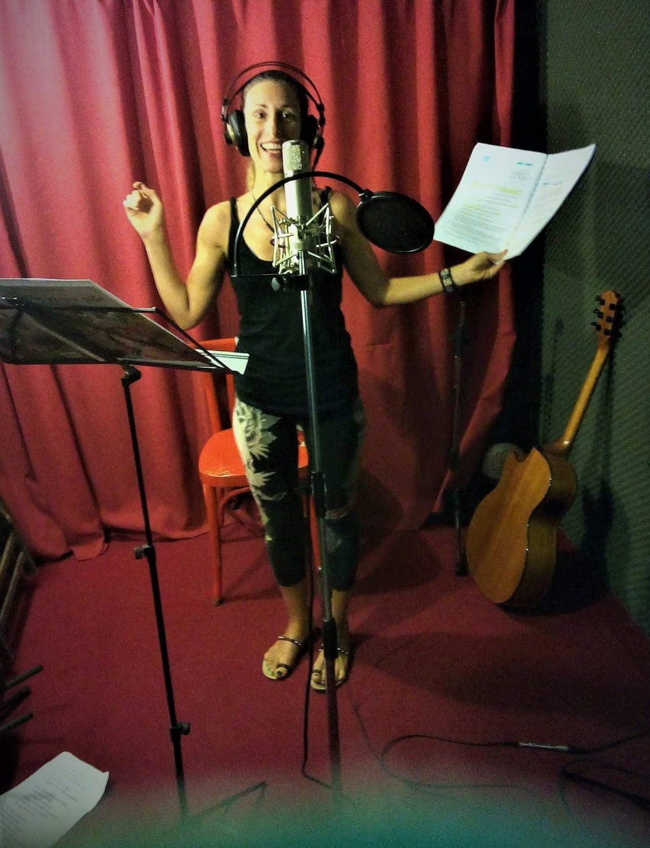 Elisabeth Theodorou recording with microphone, music stand and guitar