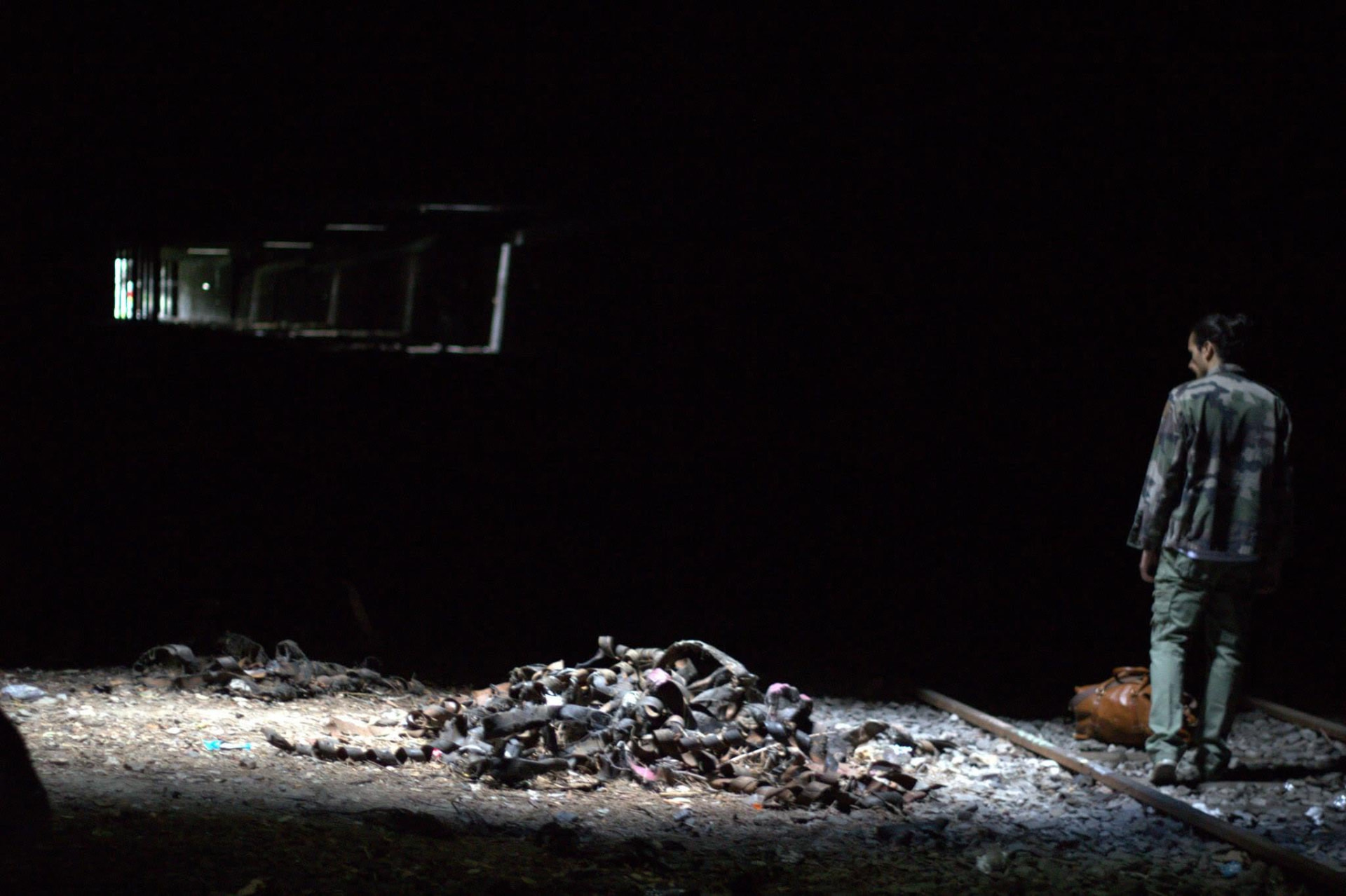 Roberto Zucco — a lone figure on a darkened stage beside the rails