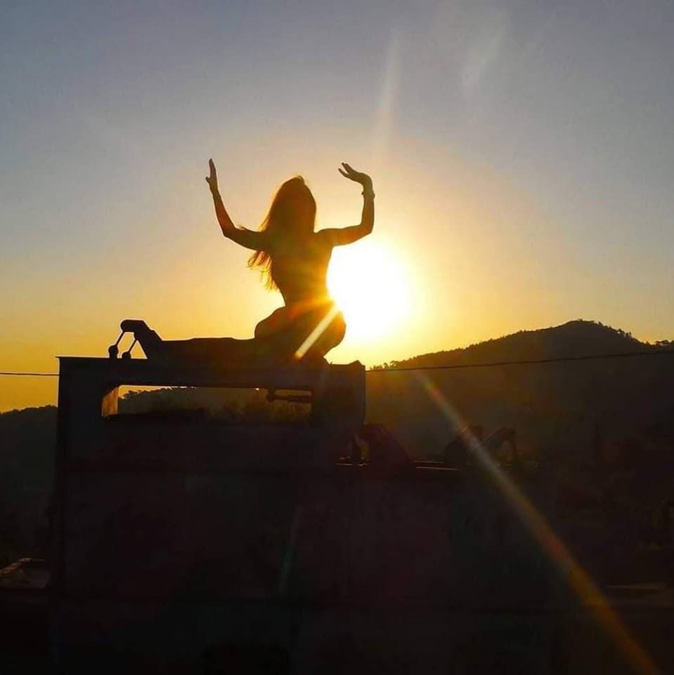 A figure raising both arms against the sun — the beginning