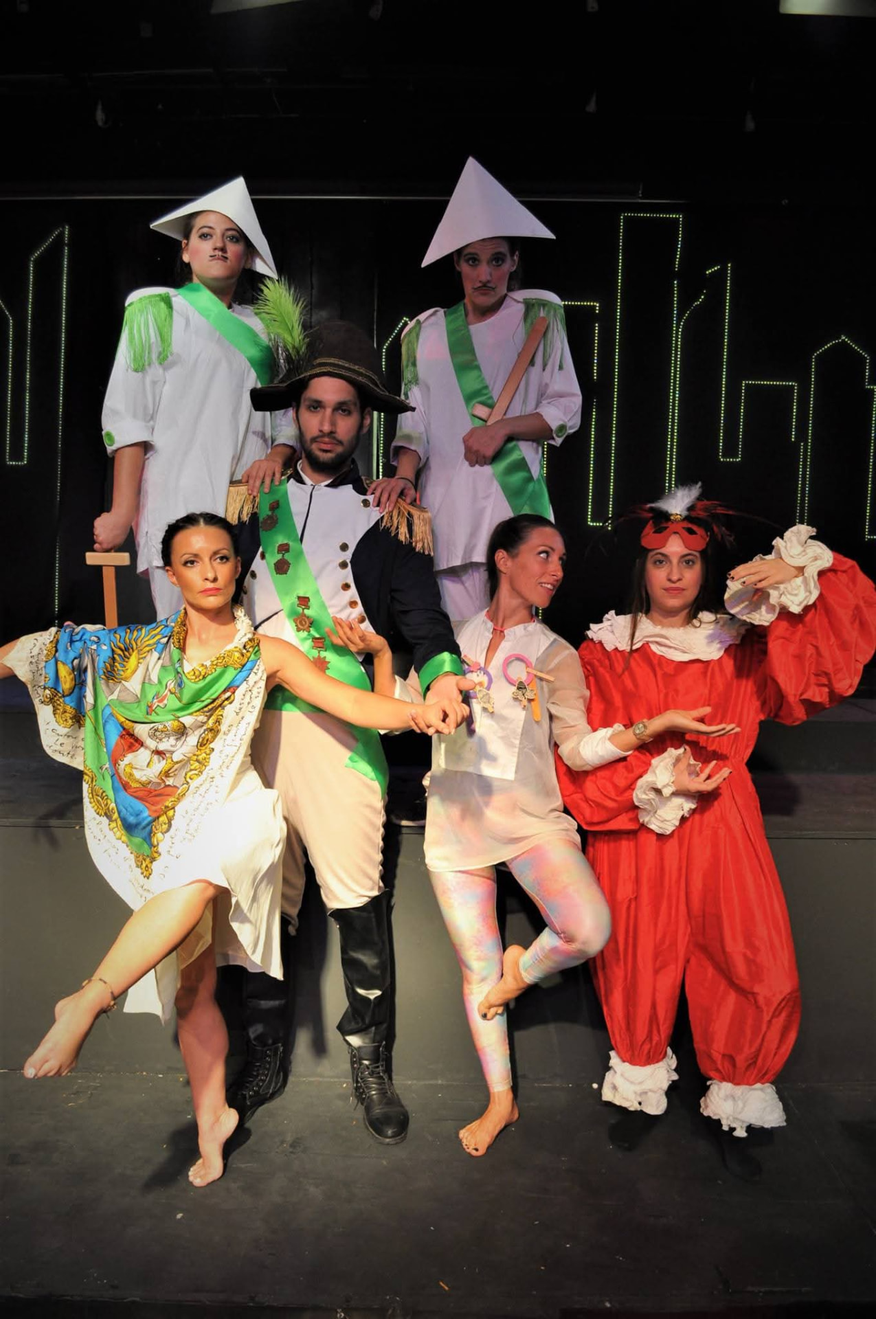 The full cast of Une ville, mais quelle ville on stage with the illuminated green city background