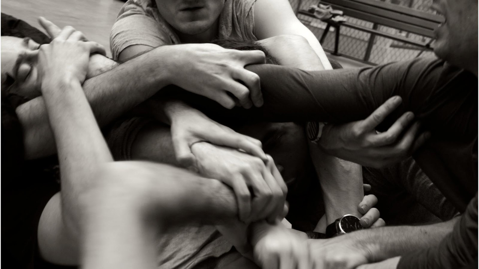 Bodies interlaced in rehearsal, hands holding and resisting